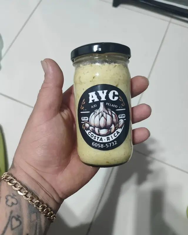 Frasco de pasta de ajo con perejil con etiqueta AYC, en la mano