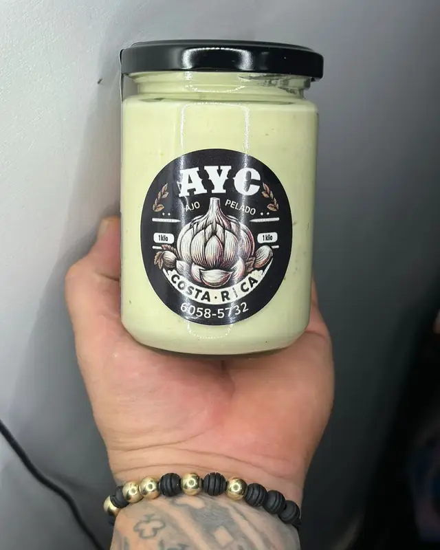 Frasco de pasta de ajo pura con etiqueta AYC, en la mano