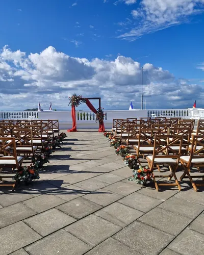 Arco de ceremonia con tela terracota y flores en una terraza
