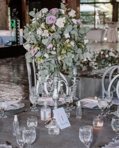 Candelabro plateado con eucalipto y rosas en una mesa de recepción