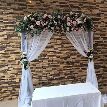 Arco con velo blanco y flores rosa y vino