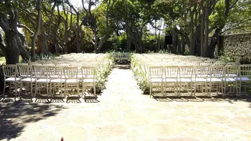 Pasillo de follaje y flores blancas entre sillas de ceremonia