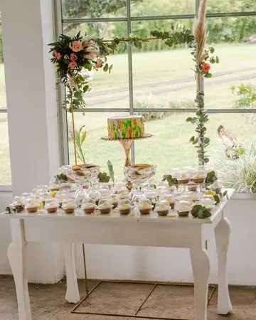 Mesa dulce con arco floral junto al ventanal