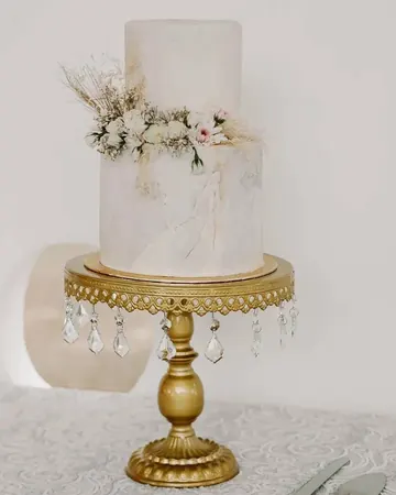 Pastel blanco con flores secas sobre base dorada