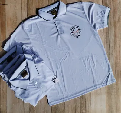 Camisas tipo polo dry fit con el escudo de una empresa, dobladas y apiladas