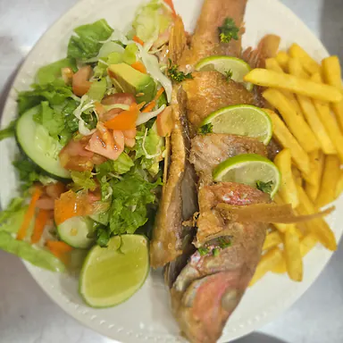 Pargo frito con ensalada, limón y papas, servido en Golden Kitchen
