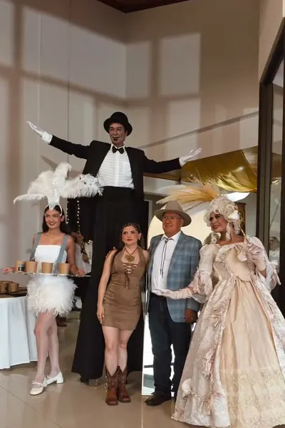 Artista en zancos con traje de gala junto a invitados de un evento privado