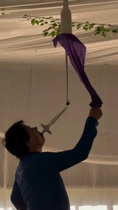 Artista equilibrando una espada y una sombrilla sobre la boca en una celebración