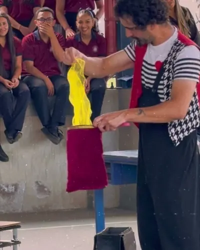 Kachevaches sacando pañuelos de colores de una bolsa frente a estudiantes