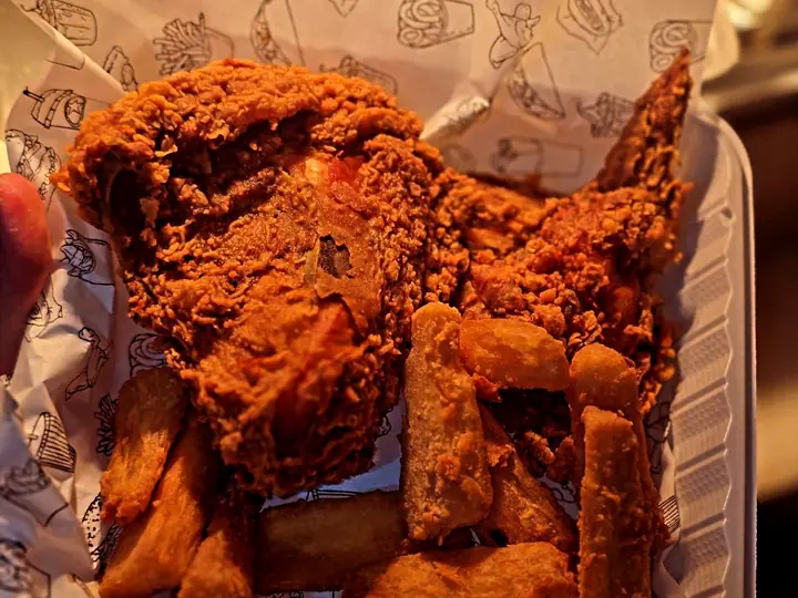 Piezas de pollo frito con papas en caja, recién servidas en Pollo Elí